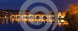 Prague, view of illuminated Charles bridge Karluv most with reflection in the water, night scenic cityscape, Czech Republic