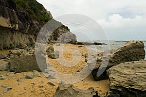 Large rocks by the sea, with waves, sand and blue sky, forming a beautiful landscape. photo