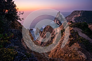 Praia da Ursa Beach at sunset. Flowers in foreground and surreal scenery. Sintra, Portugal, Europe. Atlantic Ocean