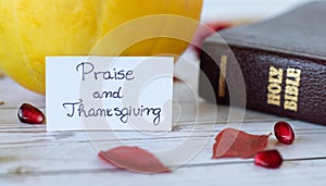 Praise and thanksgiving handwritten text message with closed Holy Bible Book, and fresh fall fruits