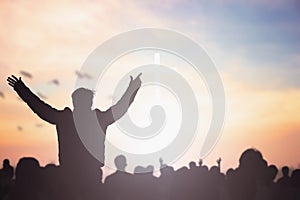 Praise and worship concept: Silhouette human raising hands to praying God on blurred cross with crown of throne sunset background