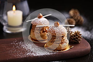 Praline hazelnut choux on wooden tray with pine for Christmas
