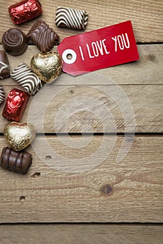 Pralines and red sign I love you on wooden background