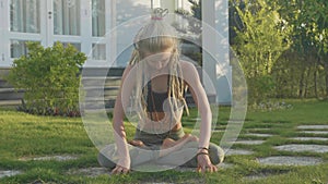 Pranayama yoga breath exercise by a young woman in the backyard of her house.