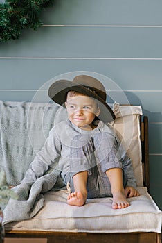 Prankster a happy child boy is sitting on the sofa in a hat that he took from his mother photo