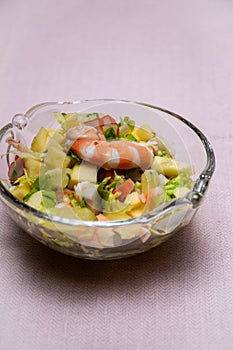 Prawn cocktail with lettuce, pink sauce, crab sticks, pineapple, apple. Glass bowl. A fresh, healthy, vegan and very healthy