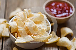 Prawn crackers chips on white bowl and wooden table background - homemade crunchy prawn crackers or shrimp crisp rice and ketchup