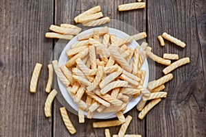 Prawn crackers stick on white plate and wooden table background , homemade crunchy prawn crackers or shrimp crisp traditional