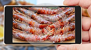 Prawn on smartphone screen. Tiger chrimp. Selling seafood in a supermarket. photo