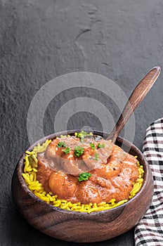 Prawn Tikka Masala with pilau rice on black stone background