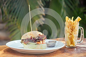 Prawns burger and french fry on table tropical sea ,palms tree and beach background