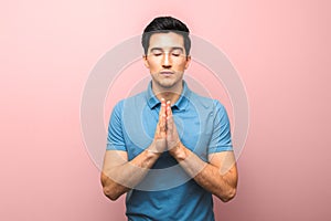 Pray for america. man in blue shirt praying for the world swallowed by coronavirus pandemic against red pink background