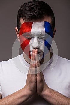 Pray France football fan in game of France national team with close eyes.