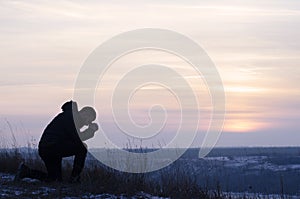 Pray. Repentance. Silhouetted men on a background of blue sky and sunset. Kneeling Prayer to God. Glorification.Praising God.