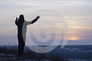 Pray. Repentance. Silhouetted men on a background of blue sky and sunset. Kneeling Prayer to God. Glorification. Praising God. A m