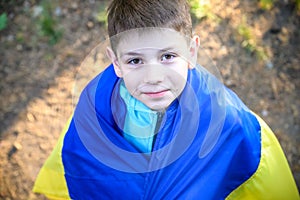 Pray for Ukraine. boy with Ukrainian flag running the summer park. Little kid waving national flag praying for peace. Happy child