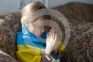 Pray for Ukraine. Child with Ukrainian flag. Little girl waving national flag praying for peace.