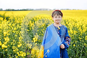 Pray for Ukraine. Child with Ukrainian flag in rapeseed field. Girl holding national flag in her hand. Happy kid celebrating