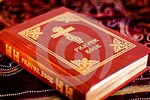 Prayer Book with Orthodox Cross on table with soft flickering candlelight