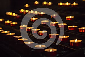 Prayer burning candles in a church on a dark background. Religious concept