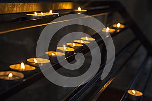 Prayer burning candles in a church on a dark background. Religious concept