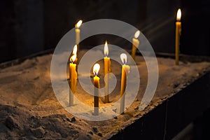 Prayer burning candles in a church on a dark background. Religious concept