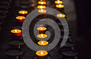 Prayer burning candles in a church on a dark background. Religious concept