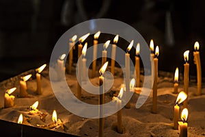 Prayer burning candles in a church on a dark background in St. Stephen`s Cathedral, Vienna. Religious concept