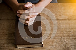 Prayer hands over a Holy Bible.