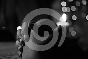 Prayer hands of a young girl with candle light on the table in black and white background. Keep praying concept. Faith love hope