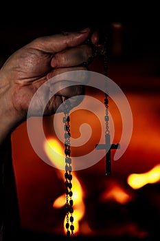 Prayer holding a crucifix or holy rosary beads, religion and praying, fire background