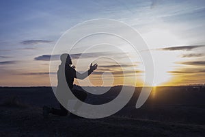 Prayer. Man on his knees praying. Against the background of the sky and sunset. Forgiveness of sins and repentance.