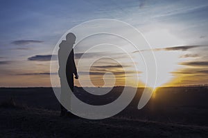 Prayer. Man on his knees praying. Against the background of the sky and sunset. Forgiveness of sins and repentance.