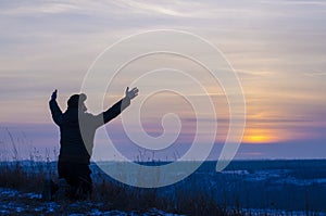 Prayer. Repentance. Silhouetted men on a background of blue sky and sunset. Kneeling Prayer to God. Glorification. Praising God photo