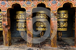 A prayer wheels on a spindle made from metal and wood. buddhist temple