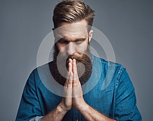 Prayerful bearded young man with palms together