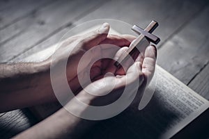 Praying with the bible and holding religious crucifix cross
