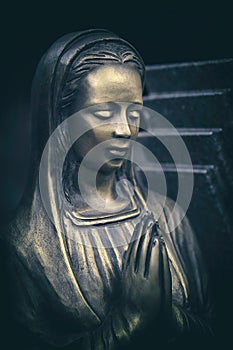 Praying bronze maria statue on tombstone
