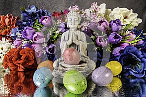 praying buddha statue with colored Easter eggs and spring flowers