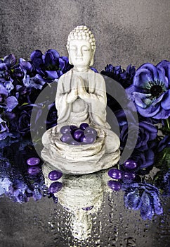praying buddha statue with purple jelly beans and blue flowers