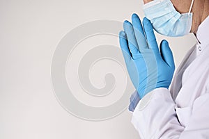 Praying doctor hands in blue rubber gloves