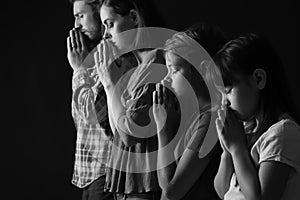 Praying family on dark background