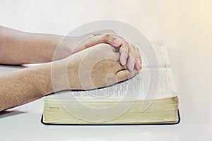 Praying hand of men on open bible book