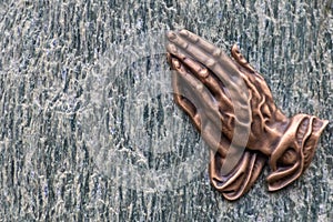 Praying hands as bronze figure on a graveyard grave as religious symbol for faith christianity blessing catholic priest and belief