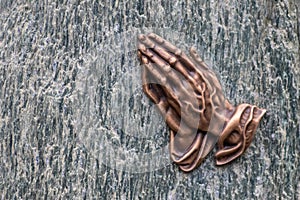 Praying hands as bronze figure on a graveyard grave as religious symbol for faith christianity blessing catholic priest and belief