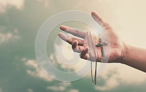 Praying hands hold a crucifix or cross of metal necklace with faith in religion and belief in God on confession background. Power photo
