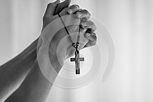 Praying hands holding a rosary.