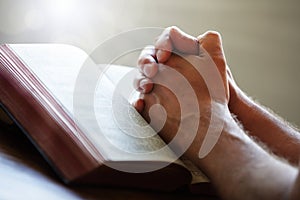 Praying hands on a Holy Bible