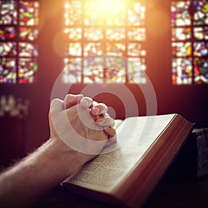 Praying hands on a Holy Bible