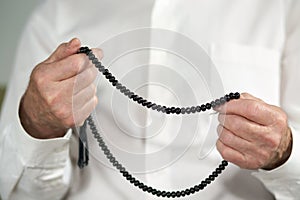 Praying hands of an old man with rosary beads